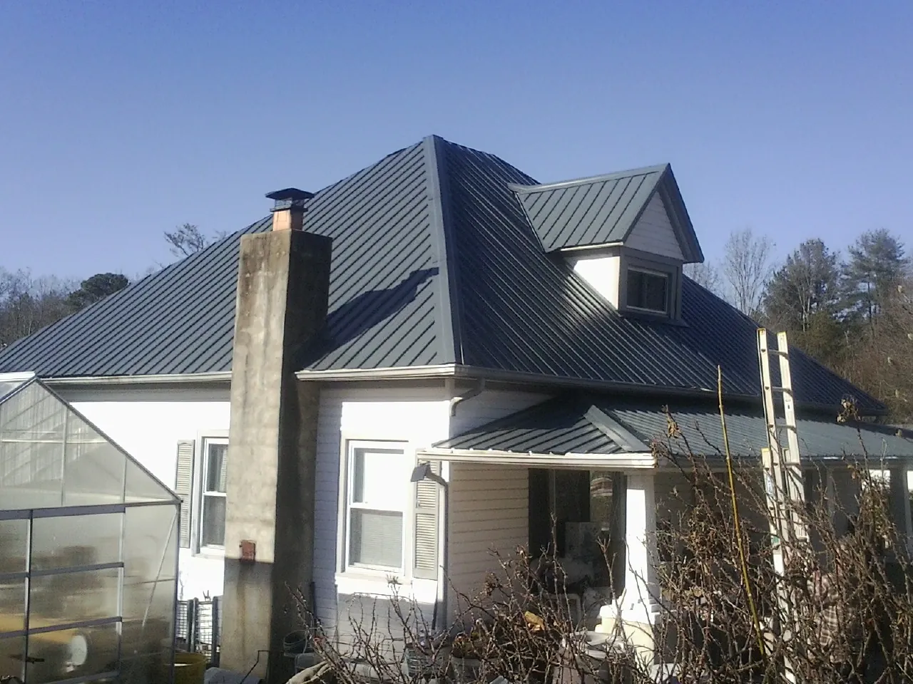 Dark blue standing seam metal roof on a white farmhouse with dormer — Slate & Tile Roof Repair by Roofing Brothers in Davidsville