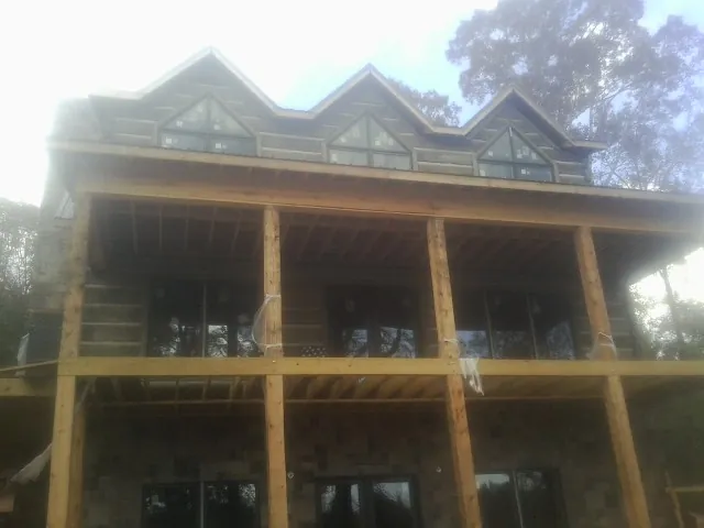 Dormers and porch framing on a large log home under construction — Roof Coating work by our crew in Davidsville