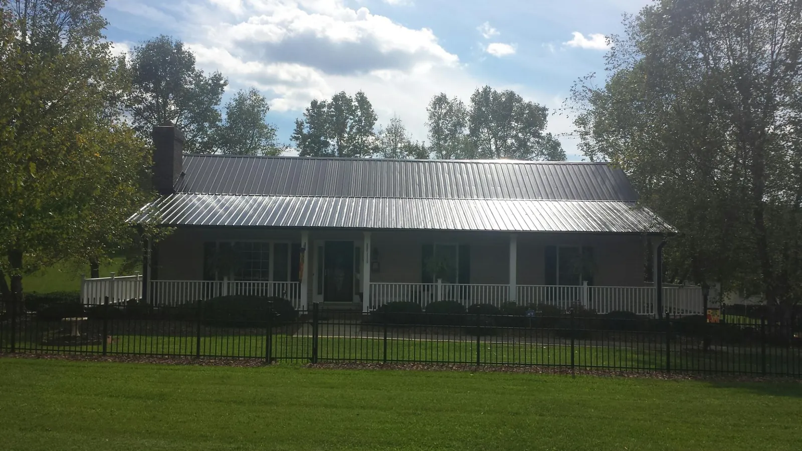 Gray metal roof on a brick ranch with a full width front porch — Gutter Guard Installation work by our crew in Davidsville
