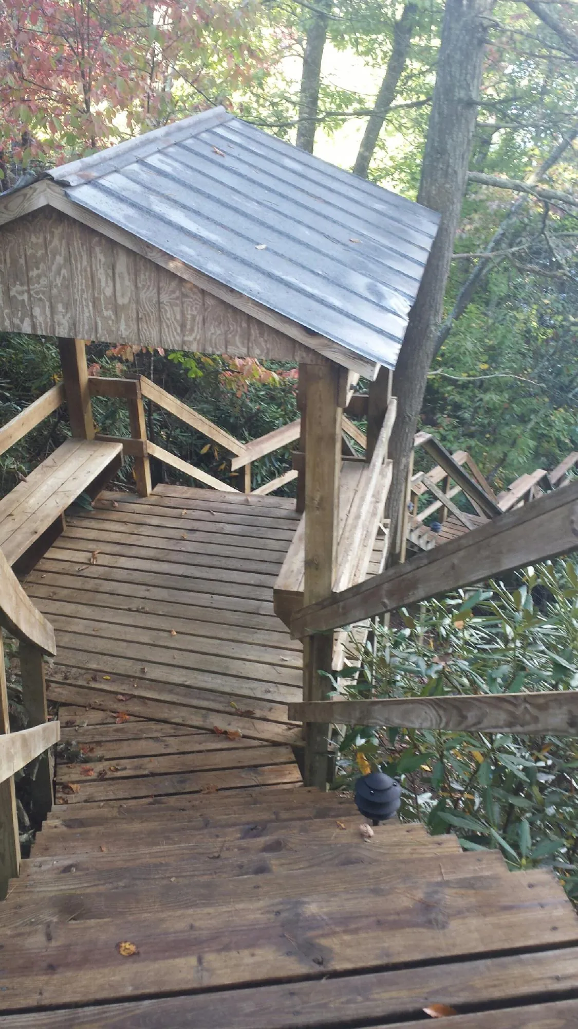 Metal roofed shelter over wooden steps on a wooded walkway — Skylight Repair & Installation work by our crew in Davidsville