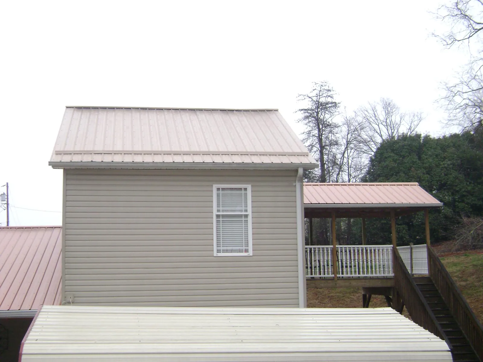 Tan metal roofs on a two story addition and attached porch, from a Roof Replacement job in Davidsville