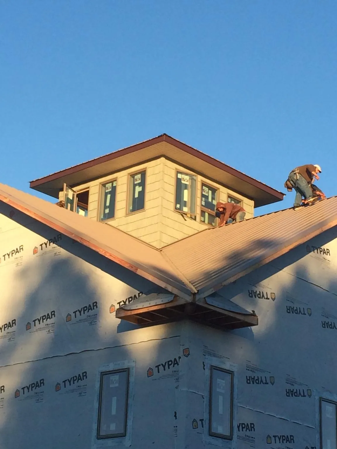 Roofers working around a rooftop cupola on a new metal roof at sunset — Roof Waterproofing in Davidsville by Roofing Brothers